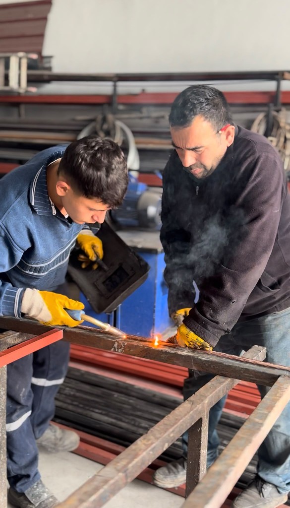 Ekip üyesi metal imalat üzerinde çalışırken