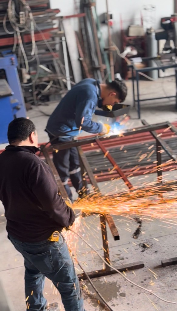 İki usta atölyede metal parçayı birlikte kaynaklarken